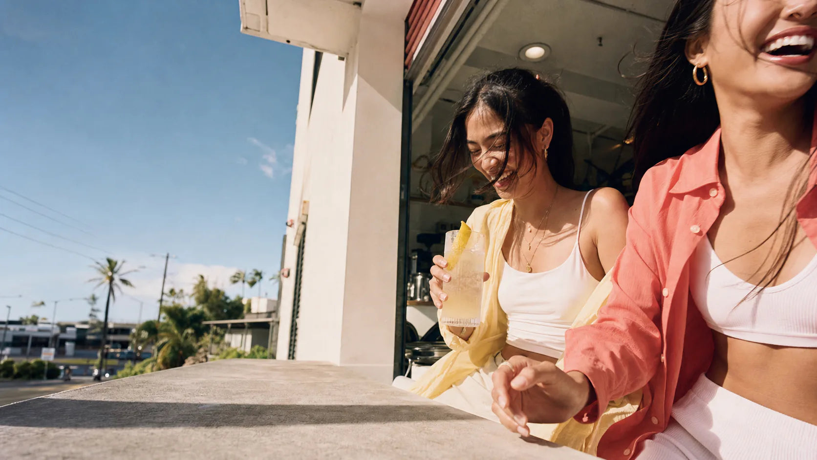 Two friends laughing outside a cafe with a cold sparkling yuzu drink